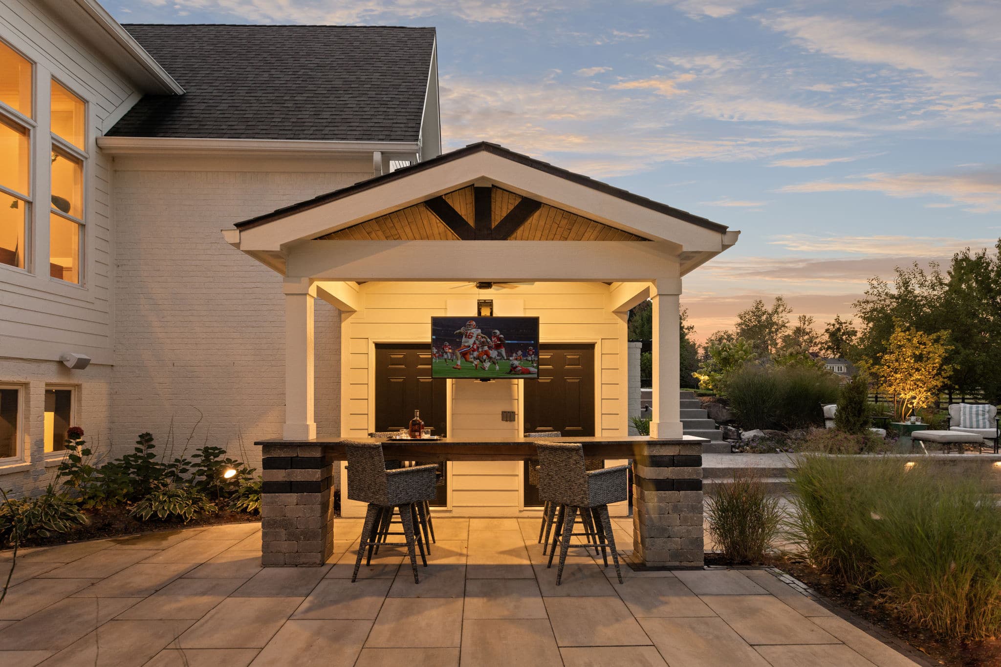 Covered outdoor living space with a bar, seating and television.