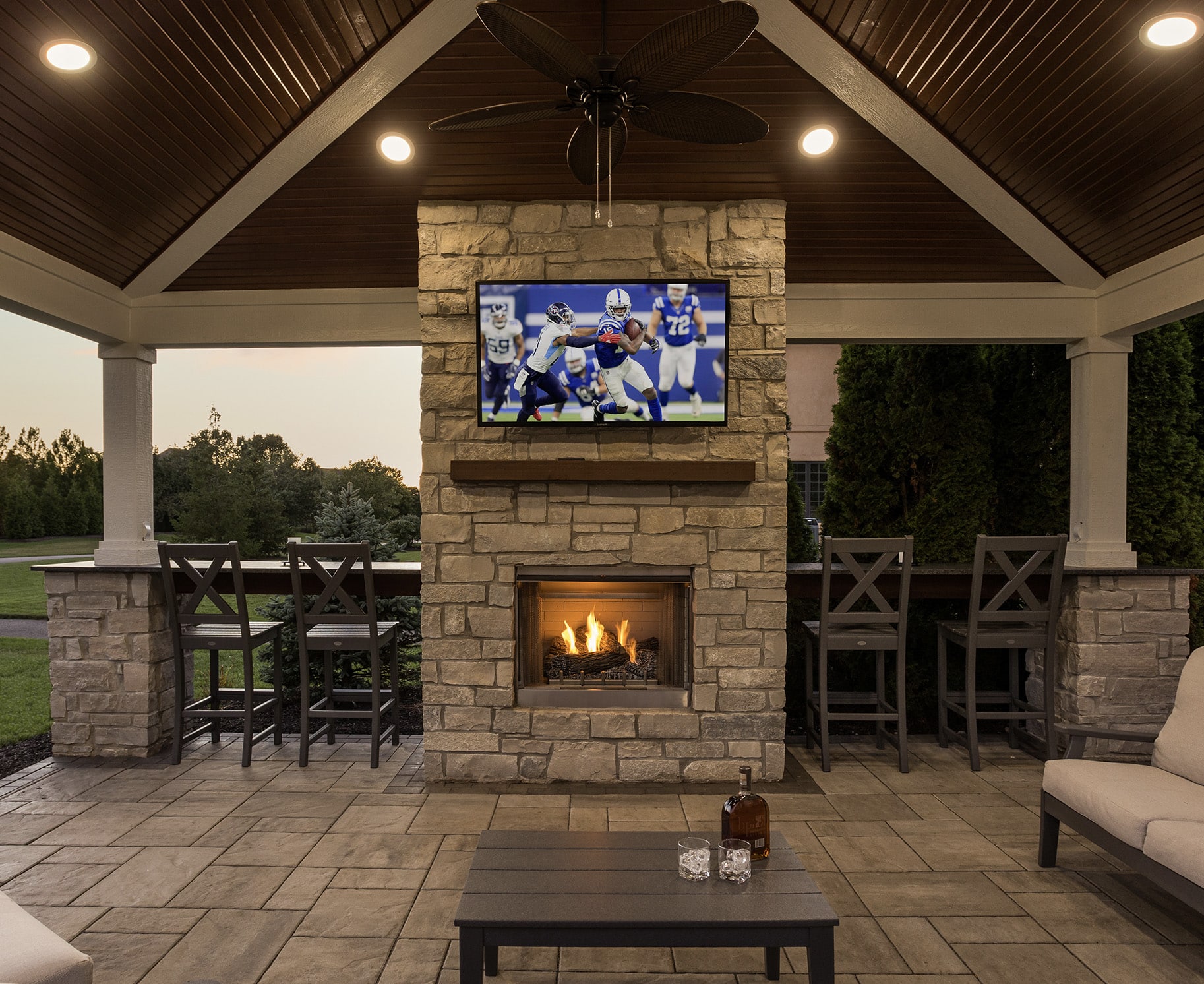 outdoor covered space with tv above fireplace and bar seating