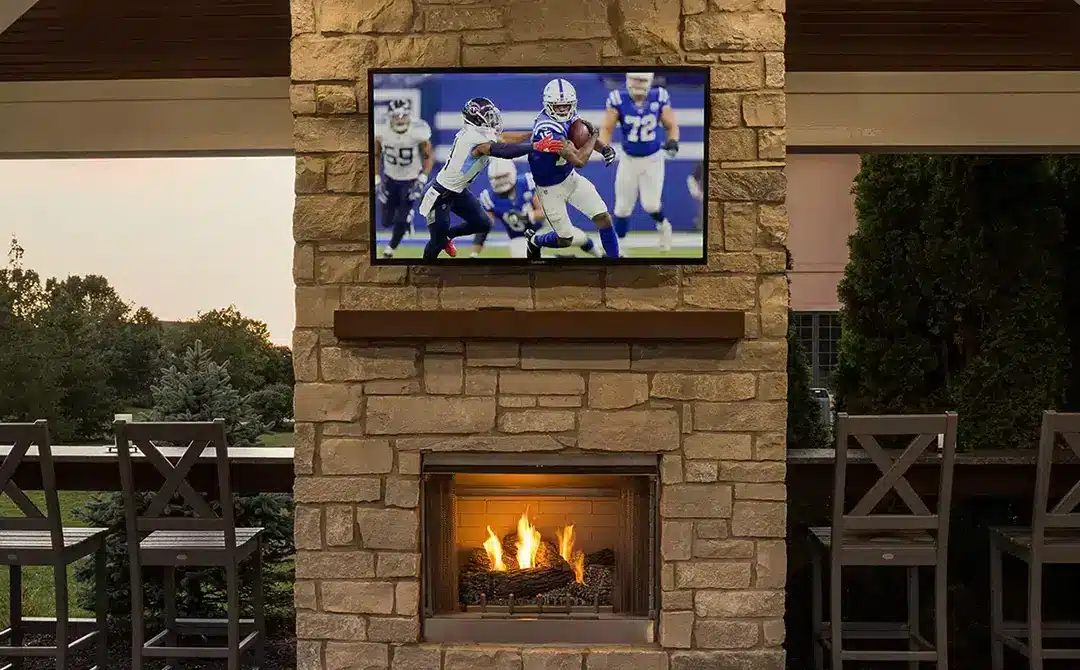 outdoor covered space with tv above fireplace and bar seating