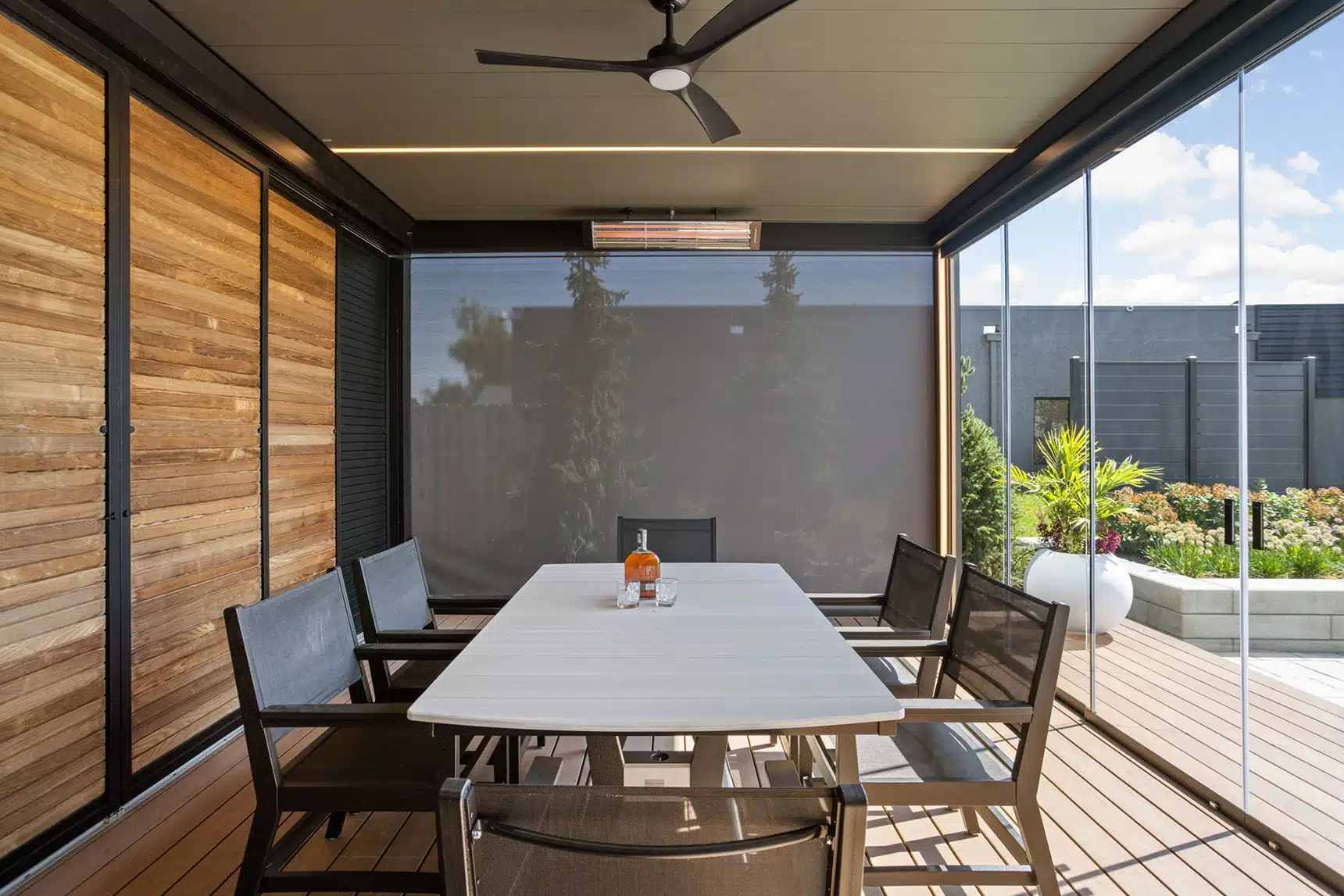 Renson pergola with privacy features including sliding glass doors, drop-down screen, and wood panels.