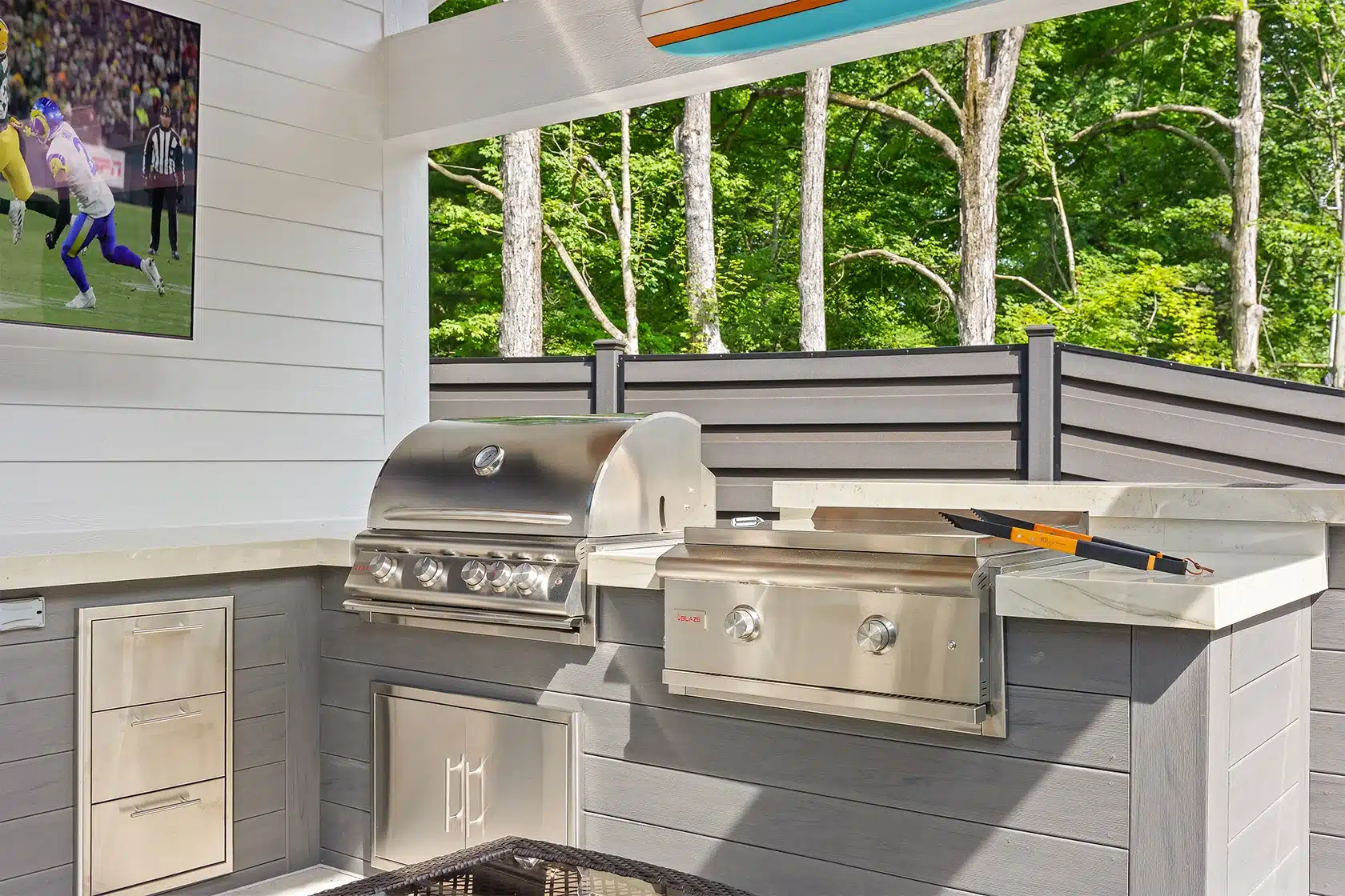 Outdoor cooking area Covered outdoor dining area with patio furniture and grill beneath a louvered pergola.