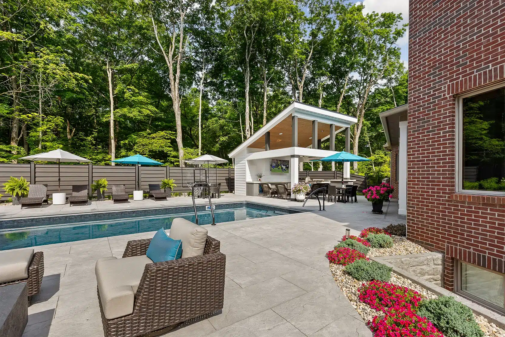 Outdoor pool area Indianapolis backyard with custom pool, covered pavilion, patio seating and colorful landscaping.
